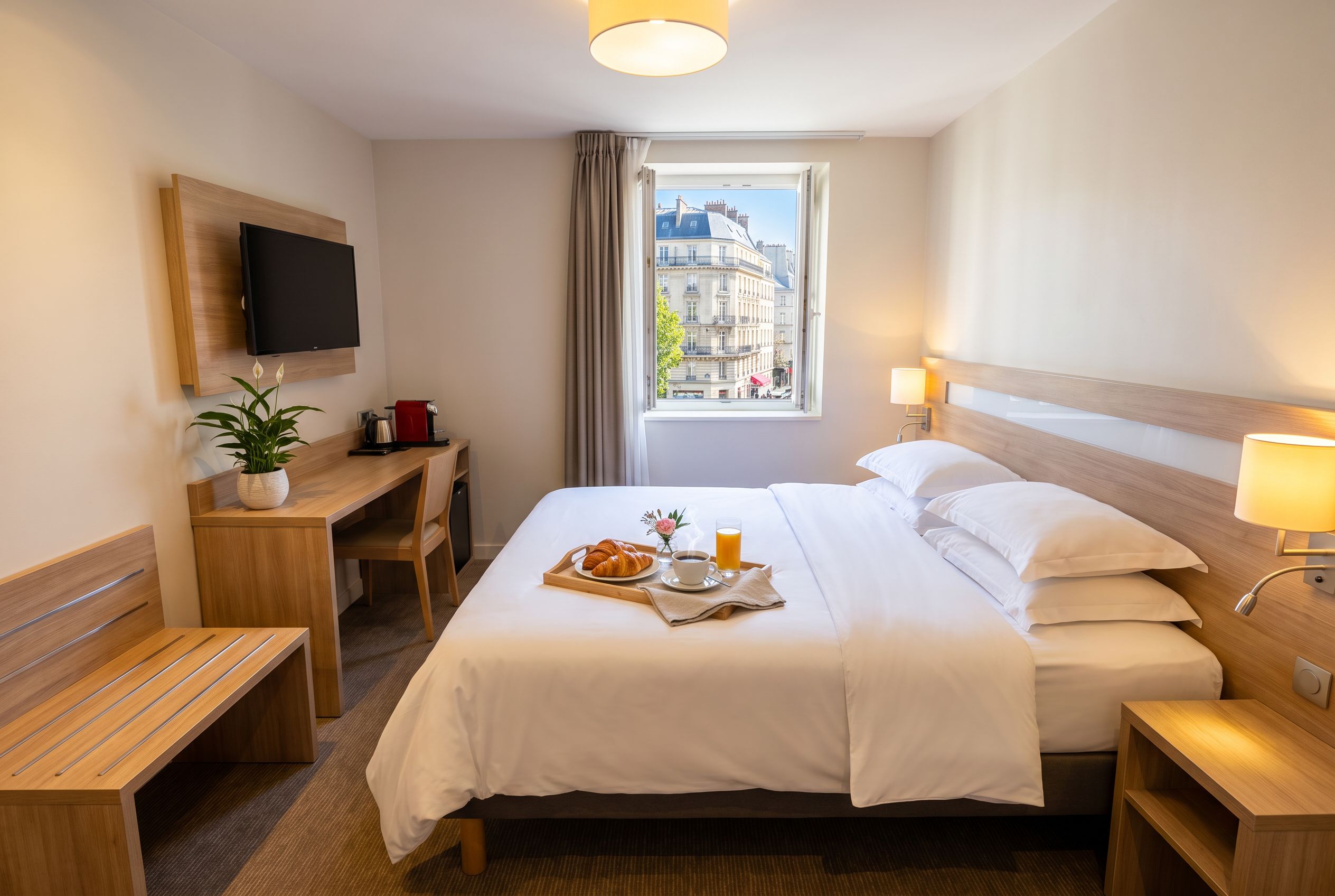 Chambre d'hôtel parisienne lumineuse avec vue, plateau petit-déjeuner et lit soigné